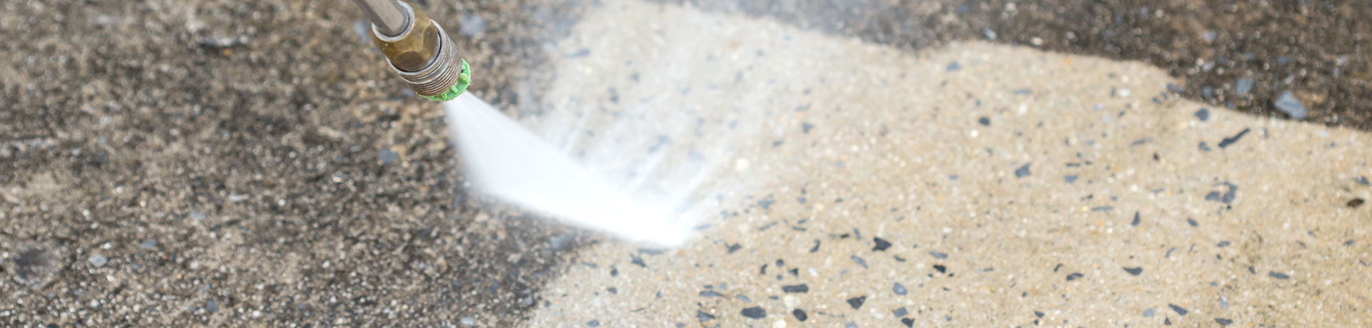 A close up image of the nozzle spraying water at high pressure to remove stubborn stains off concrete